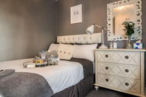 a bedroom with a bed with a dresser and a mirror at Oasis in English Village in Crowthorne