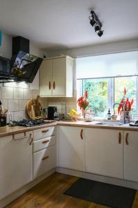 a kitchen with white cabinets and a sink and a window at Oasis in English Village in Crowthorne