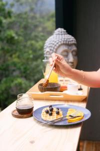 a woman eating waffles on a table next to a statue at Glamping MontdeLuxe in Yopal