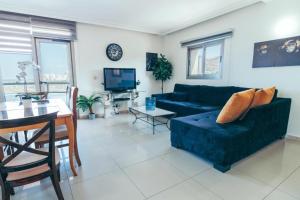 beutifull apartments by the sea في حيفا: غرفة معيشة مع أريكة زرقاء وطاولة