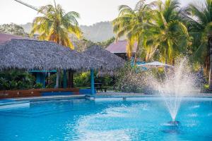 a fountain in the middle of a pool with palm trees at Beach Break Resort in Jacó