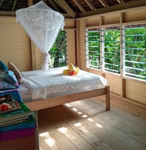 a bed in a room with two windows at Hideaway Paradise Beach Bungalows in Hog Harbour