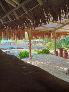 a beach with a straw umbrella and tables and benches at Hideaway Paradise Beach Bungalows in Hog Harbour