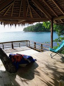 a deck with a chair and a view of the water at Hideaway Paradise Beach Bungalows in Hog Harbour
