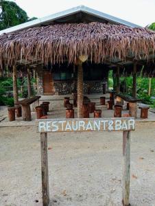un panneau devant un restaurant avec un toit de paille dans l'établissement Hideaway Paradise Beach Bungalows, à Hog Harbour