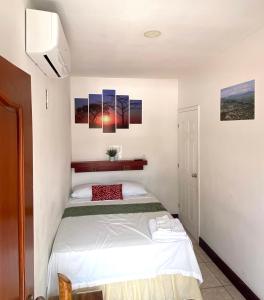 a bedroom with a bed and some paintings on the wall at Hostal San José in Somoto