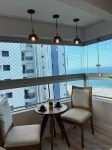 a room with a table and chairs and a large window at Lindo Apartamento 2 quartos à Beira-Mar in Vila Velha