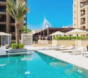 uma piscina com cadeiras e uma palmeira em Luxury Room Burj al Arab FRONT em Dubai