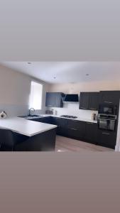 een keuken met zwarte kasten en witte aanrechtbladen bij 3 Bedroom House Near City Centre Glasgow Sleeps 7 in Glasgow