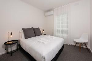 a bedroom with a white bed and a white chair at Elegant 2-bedroom House in Prahran w Parking! in Melbourne