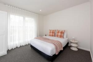 a white bedroom with a large bed and windows at Elegant 2-bedroom House in Prahran w Parking! in Melbourne