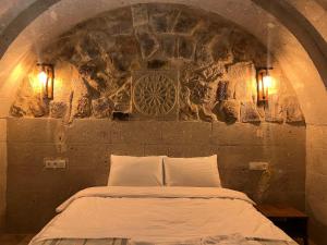 uma cama num quarto com uma parede de pedra em Cappadocıa Tuğhan Stone House em Nevşehir