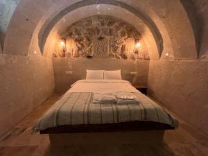 um quarto com uma cama numa parede de pedra em Cappadocıa Tuğhan Stone House em Nevşehir