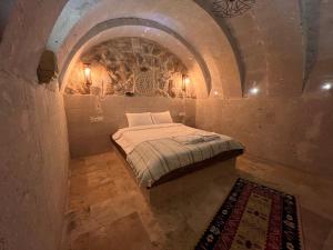 a small bedroom with a bed in a stone wall at Cappadocıa Tuğhan Stone House in Nevşehir
