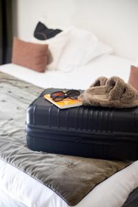 une valise assise sur un lit avec une paire de lunettes dans l'établissement Hôtel d'Angleterre, Salon-de-Provence, à Salon-de-Provence