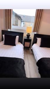 two beds in a room with a window at 3 Bedroom House Near City Centre Glasgow Sleeps 7 in Glasgow