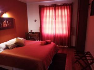 1 dormitorio con cama y ventana roja en Hotel Casa Ecuatreasures Centro Historico, en Quito
