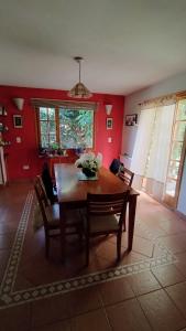 stół jadalny i krzesła w pokoju z czerwonymi ścianami w obiekcie Casa de Silvina w mieście El Bolsón