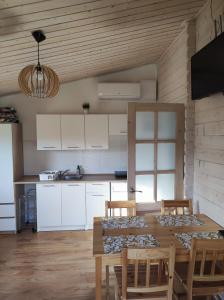 a kitchen with a wooden table with chairs and a dining room at Domki Zaczarowana Łąka w Borach Tucholskich in Wełpin +48 photos