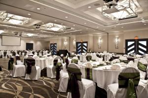 un salón de banquetes con mesas y sillas blancas en Coast Bastion Hotel, en Nanaimo