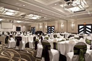 um salão de banquetes com mesas e cadeiras brancas em Coast Bastion Hotel em Nanaimo