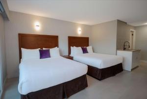 2 camas en una habitación de hotel con almohadas blancas y moradas en Coast Metro Vancouver Hotel, en Burnaby