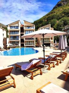 ein Pool mit Stühlen und Sonnenschirmen neben einem Hotel in der Unterkunft Blue Horizon Apartment Lena in Pržno