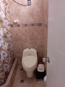 a bathroom with a toilet in a tiled room at Departamentos en Playa Pulpos HOSPEDAJE DELFINES HOUSE in Lurín