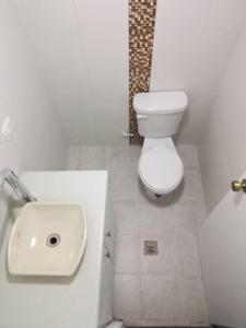 a white bathroom with a toilet and a sink at Apartamento Edificio Tuncahuan, 12 de octubre a 50mts Swissotel in Quito