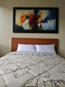 a bed in a bedroom with a picture on the wall at Apartamento Edificio Tuncahuan, 12 de octubre a 50mts Swissotel in Quito