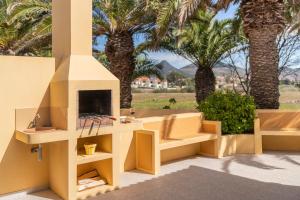 eine Terrasse mit Pizzaofen und Palmen in der Unterkunft Casa do Ribeiro Salgado by An Island Apart in Porto Santo