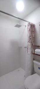 a white bathroom with a toilet and a shower at Hostal El Recreo in Barranquilla
