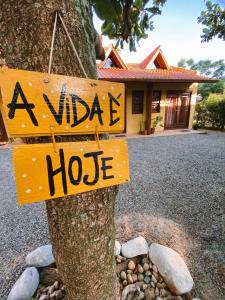 a wooden sign on a tree in front of a house at Pousada Chalé Caminho da Guarda in Palhoça