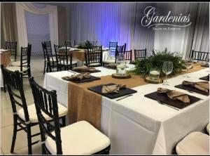 - une table avec des tables et des chaises blanches dans la chambre dans l'établissement Baja Inn Hoteles La Mesa, à Tijuana