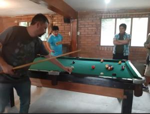 a man playing a game of pool with a cue at Cabañas Campestres Villa Bella in Coroico Viejo