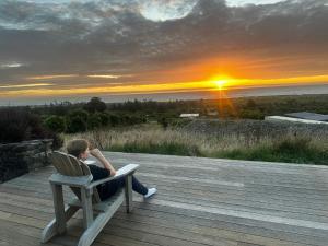 un homme assis sur une chaise et regardant le coucher du soleil dans l'établissement Rataview, à Barrytown