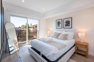 a white bedroom with a large bed and a balcony at Deluxe Modern 2-bedroom Condo w/ Roof Deck! in Los Angeles