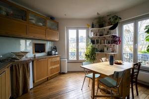 une cuisine avec une table en bois et une salle à manger dans l'établissement Nice Appartment near Buttes Chaumont, à Paris