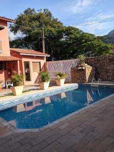 a swimming pool in front of a house at Chalés Caraguá Massaguaçu in Caraguatatuba
