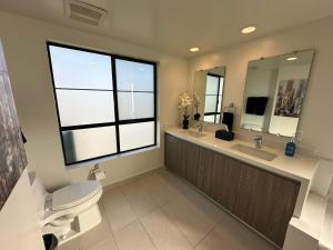 a bathroom with a toilet and a sink and a mirror at The Century City Cozy 3 Bedroom Apartment with free parking! in Los Angeles