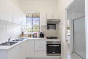 a white kitchen with a sink and a stove at Bright & Cosy 1-Bed 15-Min From CBD in Brisbane