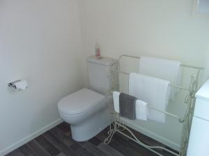 a bathroom with a toilet and towels on a rack at Chris and Dave's B & B in Otorohanga