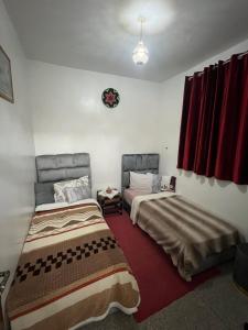 twee bedden in een kamer met rode gordijnen bij Youss Appartement in Essaouira