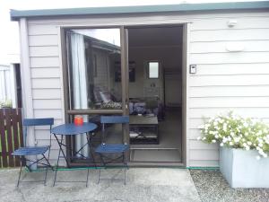 eine Terrasse mit einem Tisch und Stühlen neben einer Tür in der Unterkunft Chris and Dave's B & B in Otorohanga