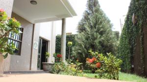 a porch of a house with a tree and flowers at Hotel Residence Flamani in Lomé
