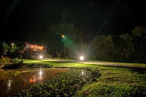 une maison la nuit avec des lumières dans l'herbe dans l'établissement Cabanas da Fazenda / 02, à Gramado