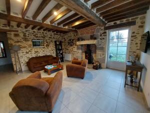 sala de estar con muebles de cuero y pared de piedra. en Gîte Saint-Calais-du-Désert, 4 pièces, 6 personnes - FR-1-600-161, en Saint-Calais-du-Désert