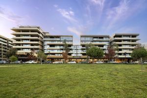 a large apartment building with cars parked in a field at Stylish 2-Bed with Amenities 10-Min from CBD in Campbell