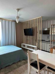 um quarto com uma cama, uma mesa e uma televisão em Flat aconchegante em Piratininga 100 mt da praia em Niterói
