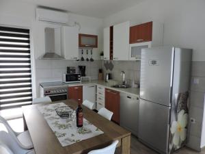 een keuken met een tafel en een koelkast bij Family friendly house with a swimming pool Sestanovac, Zagora - 22984 in Šestanovac
